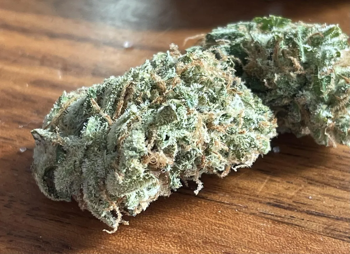 Two vibrant, trichome-rich cannabis buds on wood, indicative of quality found in Utrera social clubs.